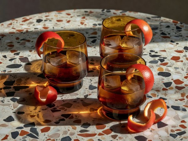Smoked amber aperitivo glasses with ice and blood orange peel on a honed terrazzo tabletop